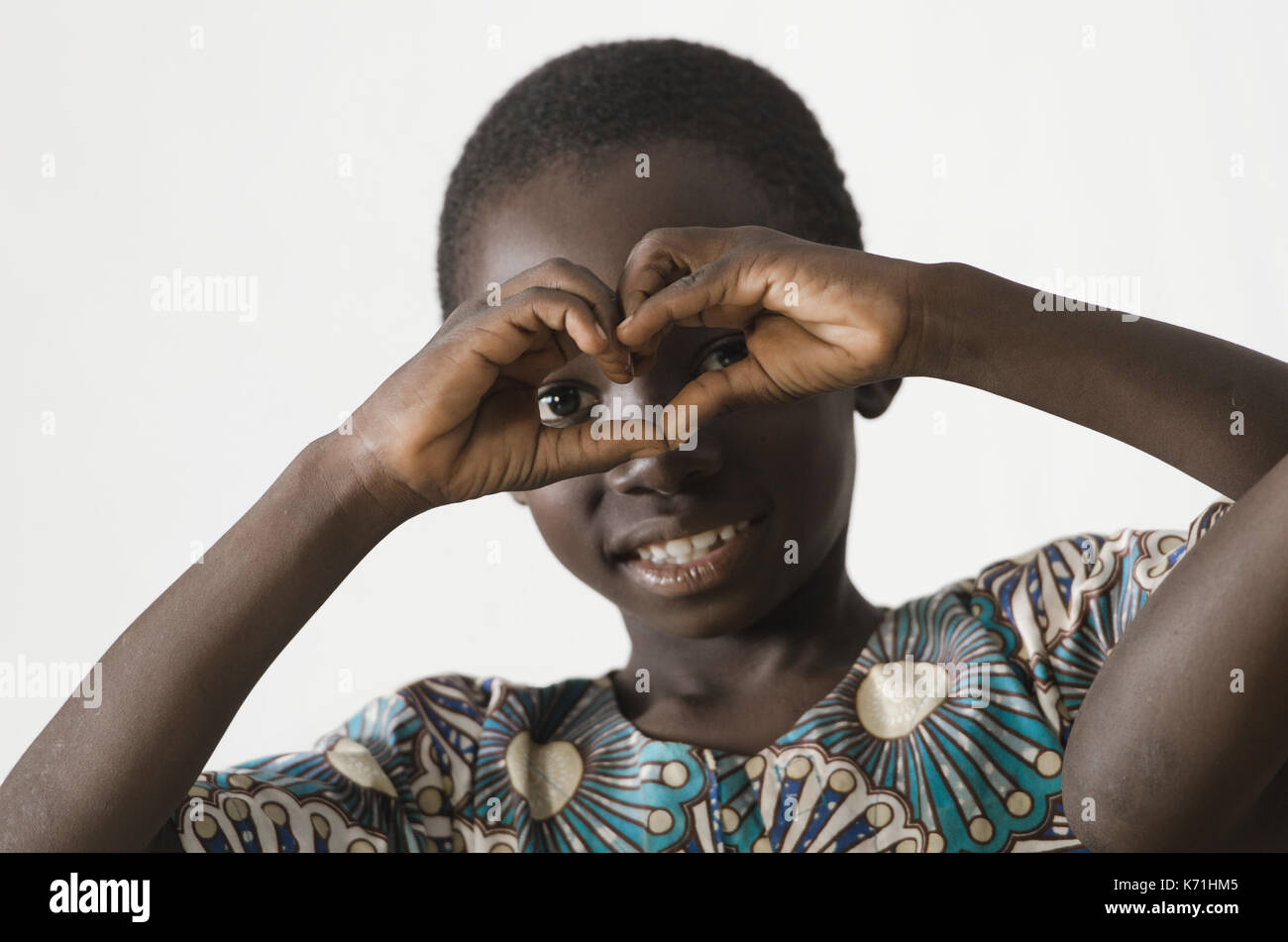 Petit enfant noir de l'Afrique montrant le symbole de coeur avec ses mains, isolated on white Banque D'Images