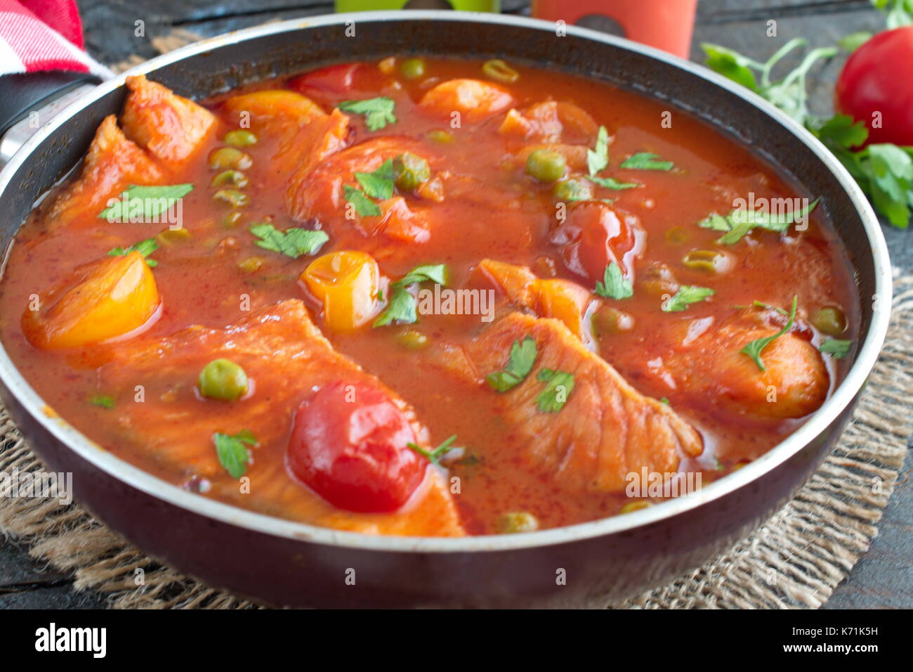Filet de poisson cuit dans une sauce tomate avec des pois verts et tomates cerises sur une plaque sur un fond de bois sain eting. concept. Une cuisine facile. Banque D'Images