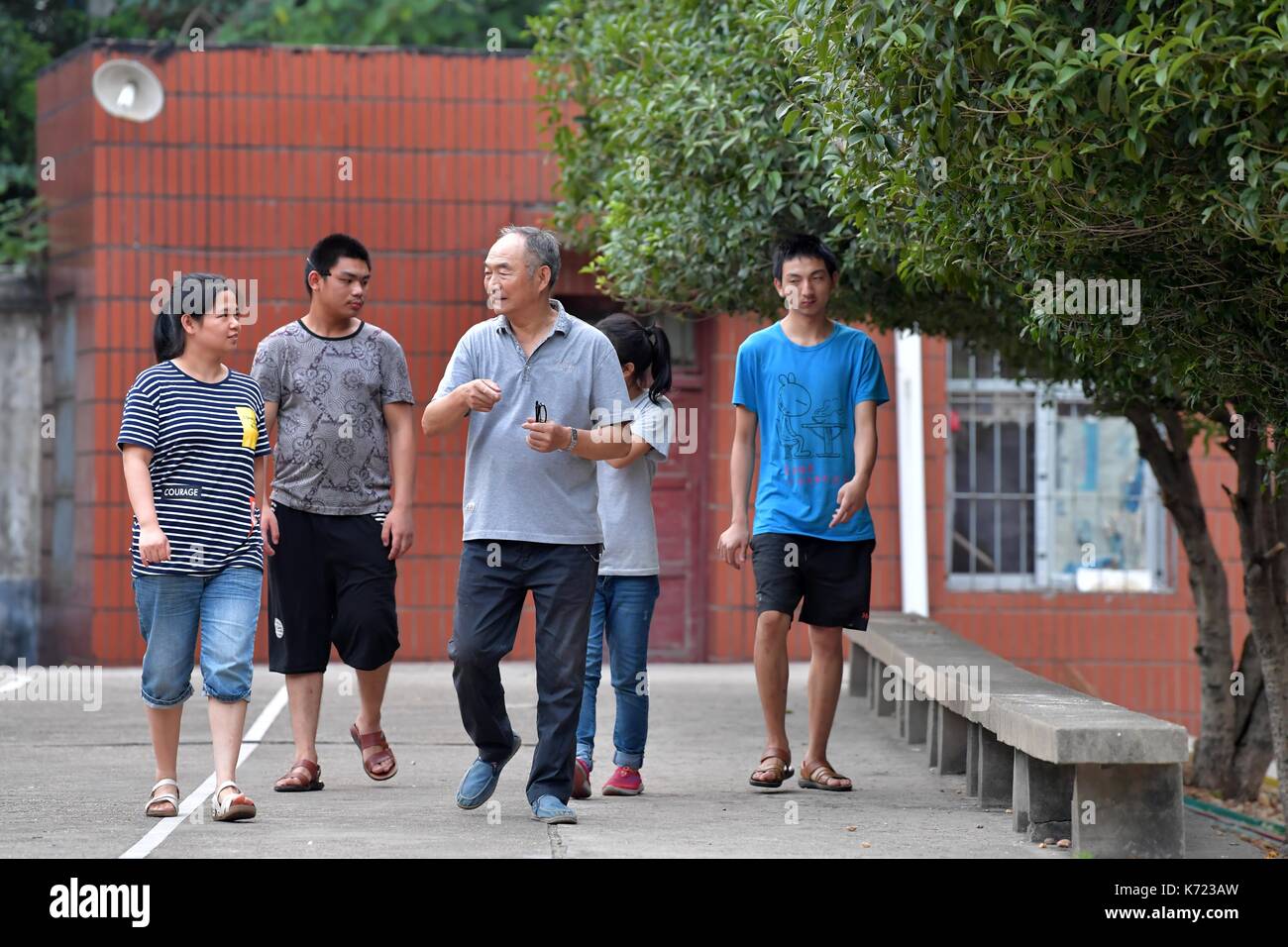 (170914) -- nanchang, sept. 14, 2017 (Xinhua) -- il xingwu fait une promenade avec les élèves d'une école spéciale à Nanchang, province de Jiangxi en Chine de l'Est, sept. 13, 2017. Les 74 ans, enseignant, il xingwu a travaillé dans l'école spéciale depuis 23 ans. Il a perdu l'audition à l'âge de huit ans en raison de l'utilisation inappropriée de médicaments. En 1994, lui et son ami a fondé l'école après sa retraite. plus de 300 à l'audition et des malentendants francophones les étudiants ont obtenu un diplôme de l'école. (Xinhua/peng zhaozhi) (zkr)(zt) Banque D'Images