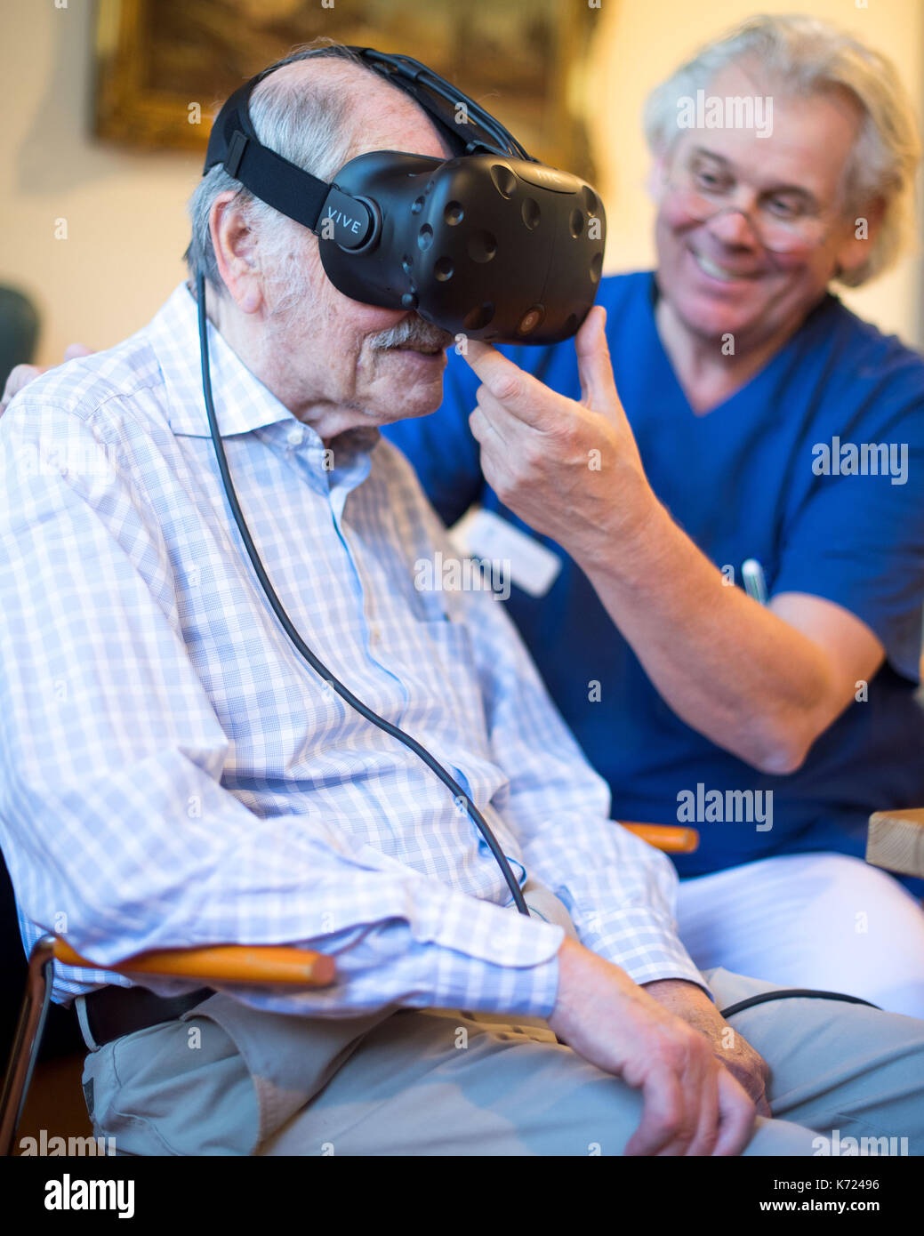 Friedhelm caspers, chef gériatrie médecin, mettre une paire de lunettes de réalité virtuelle sur un patient atteint de démence dans creveld, Allemagne, 14 septembre 2017. assistance numérique devrait ralentir les processus de démence et d'Alzheimers. Les patients peuvent se déplacer à travers des scènes de rue à partir des années 1950, et ainsi faire un voyage dans leur propre passé. photo : marius becker/dpa Banque D'Images