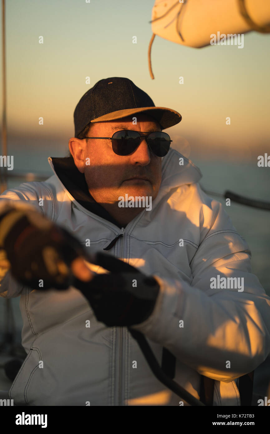 Yachtsman assis sur le bateau pendant le coucher du soleil Banque D'Images