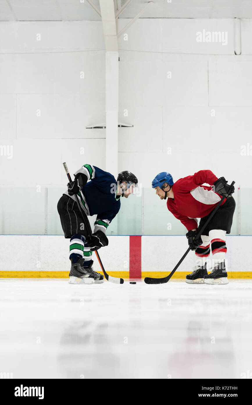 Vue latérale pleine longueur de joueurs de hockey sur glace à la patinoire face à face à Banque D'Images