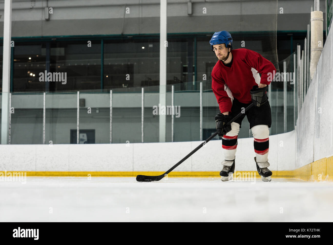 Toute la longueur de l'homme déterminé joueur de jouer au hockey sur glace rink Banque D'Images