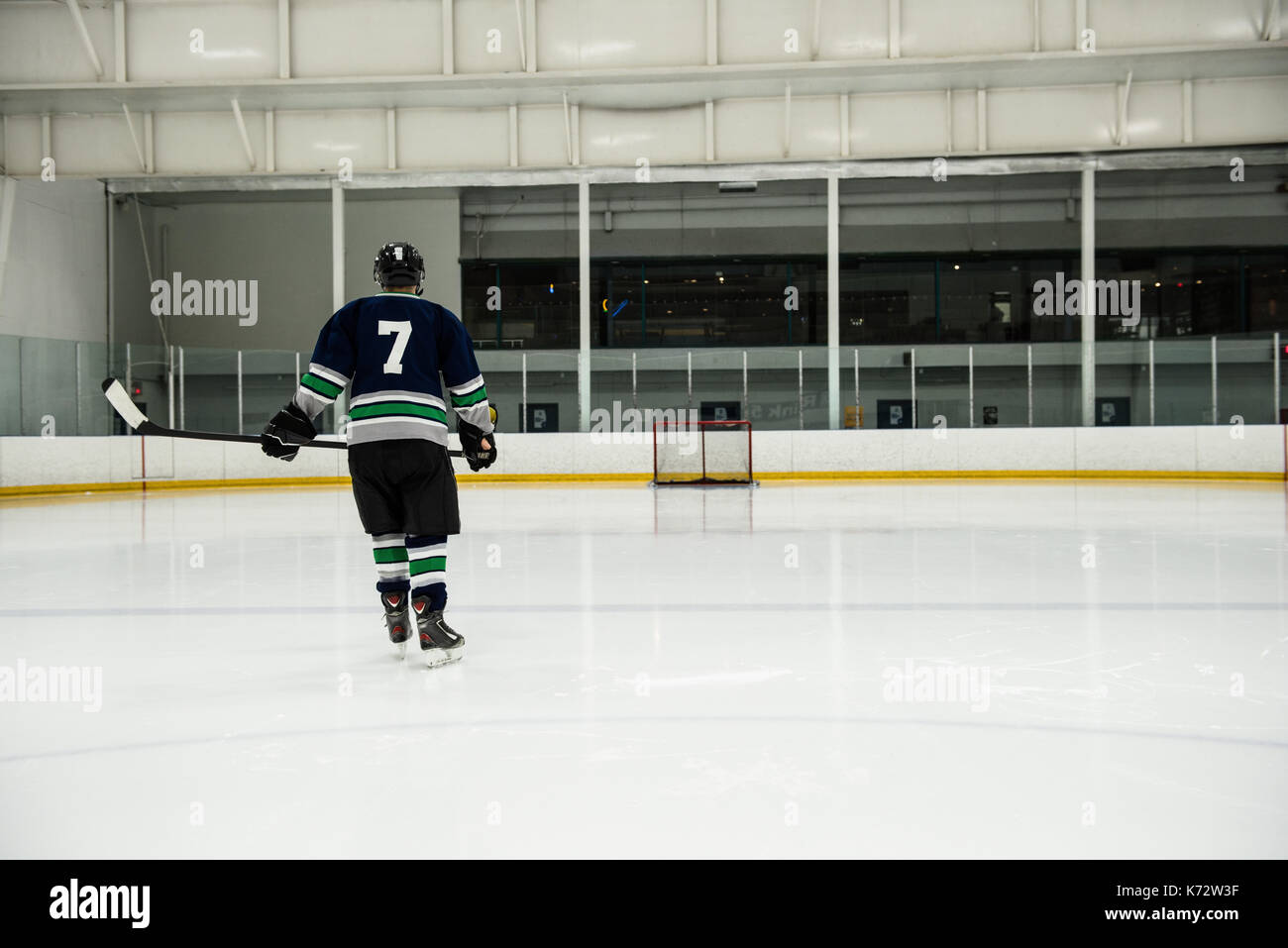 Vue arrière du joueur de hockey sur glace masculin holding stick at rink Banque D'Images