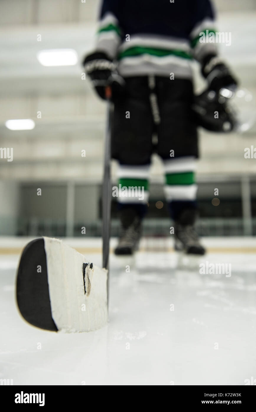 La section basse de joueur de hockey sur glace masculin holding stick at rink Banque D'Images