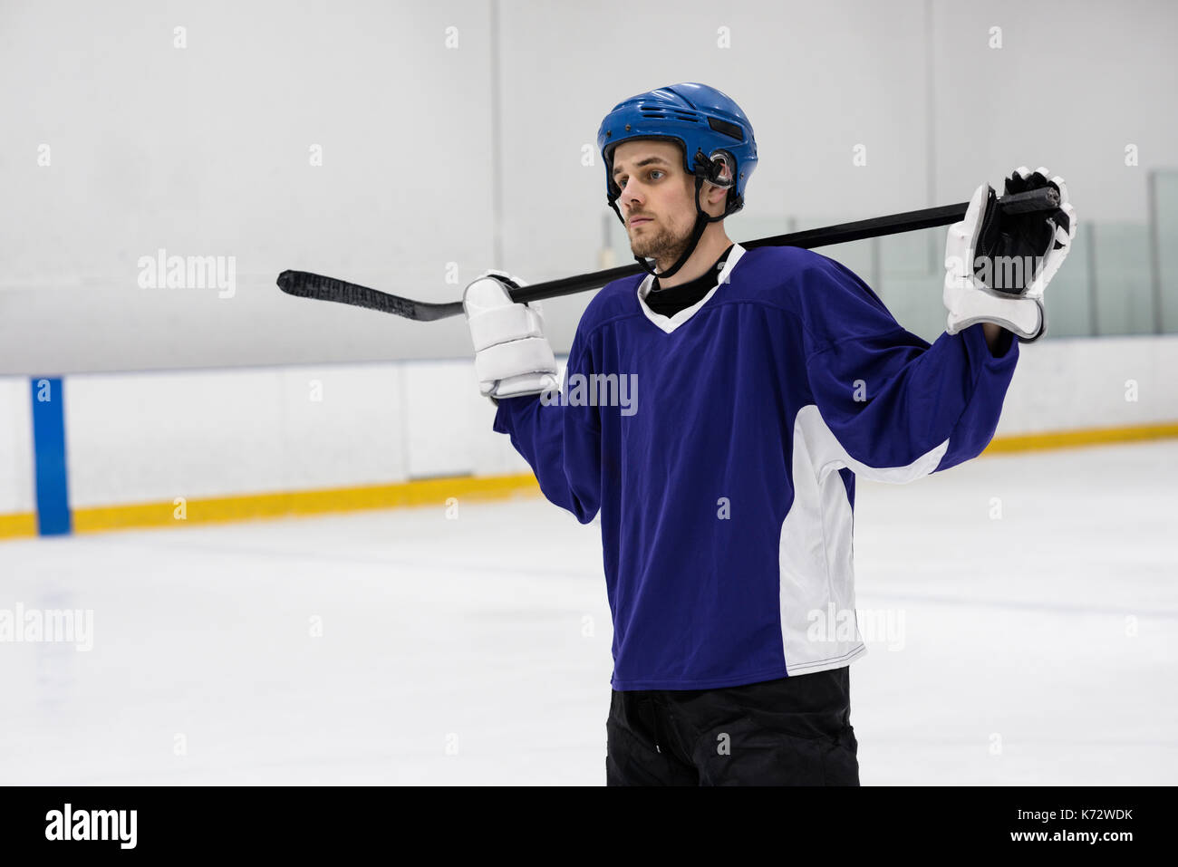 Joueur de hockey sur glace masculin holding stick tout en se tenant au rink Banque D'Images