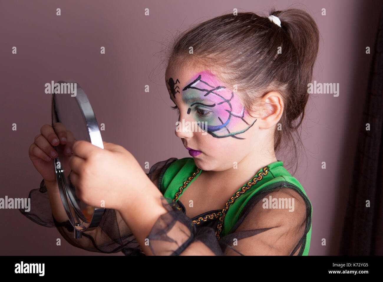Petite fille à la recherche dans le miroir après la peinture du visage session avant Halloween party Banque D'Images