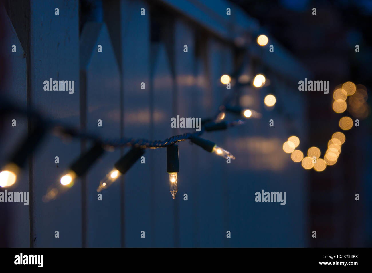 Les lumières de Noël en lumière tamisée drapé sur une clôture résidentielle Banque D'Images