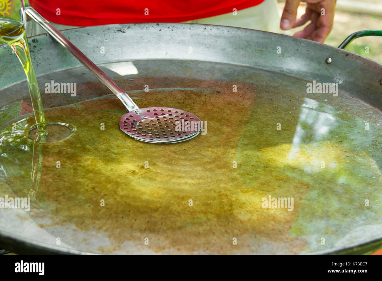 Grande télévision poêle ou poêlon pour la paella ou jambalaya sur brûleur gaz. processus de coulée et le chauffage de l'huile d'olive pour la cuisson du riz viande légumes. man Banque D'Images