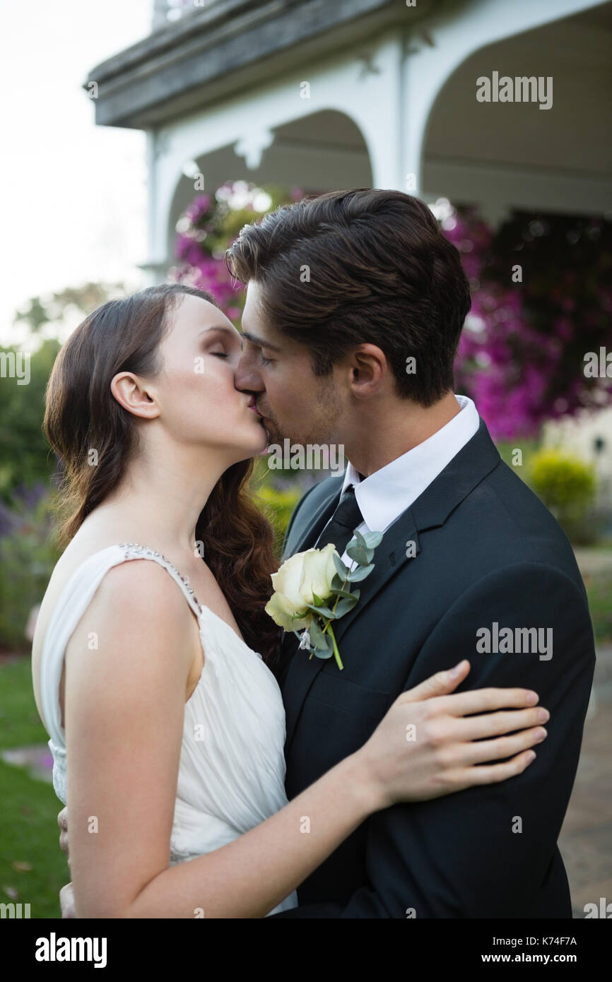 Romantic newlywed couple s'embrasser tout en se tenant dans park Banque D'Images
