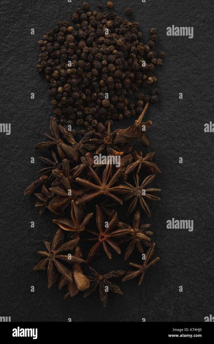 Close-up of star anises et poivrons noirs sur fond noir Banque D'Images