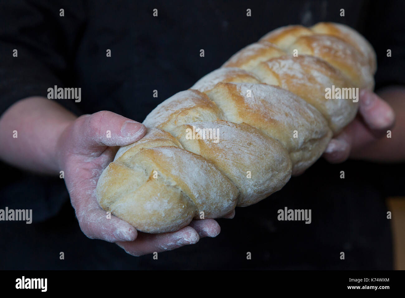 : Boulangerie pain cuit dans un four à bois. Baker tenant un pain tressé à la main Banque D'Images