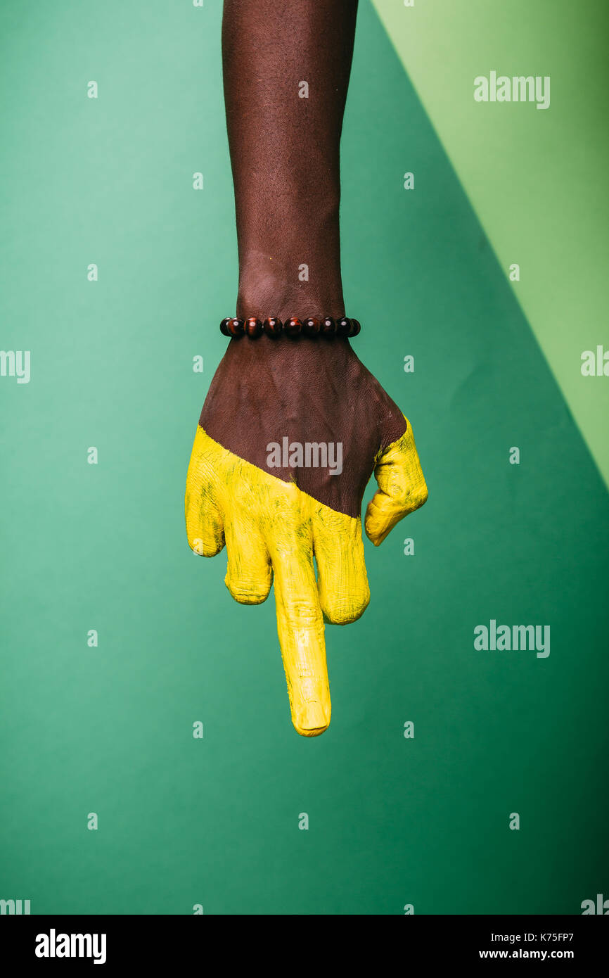 Une femme part, african american peint en vert côté peau, fond vert, bijoux bracelet, geste majeur Banque D'Images