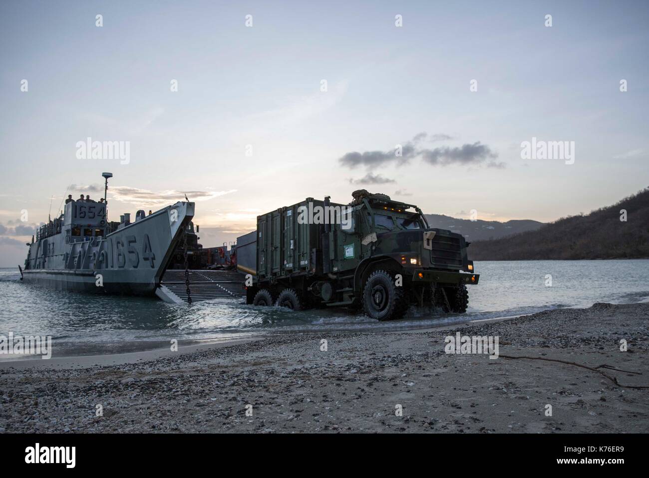 Un camion transportant de l'équipement et des fournitures en débarque un landing craft utility Banque D'Images