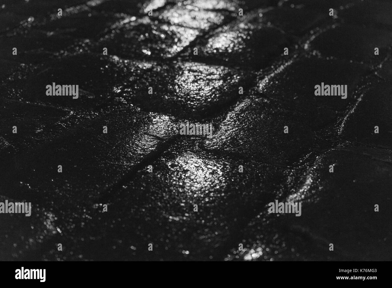 Nuit de réflexion de la lumière sur les pavés humides après la pluie. image en noir et blanc avec selective focus Banque D'Images