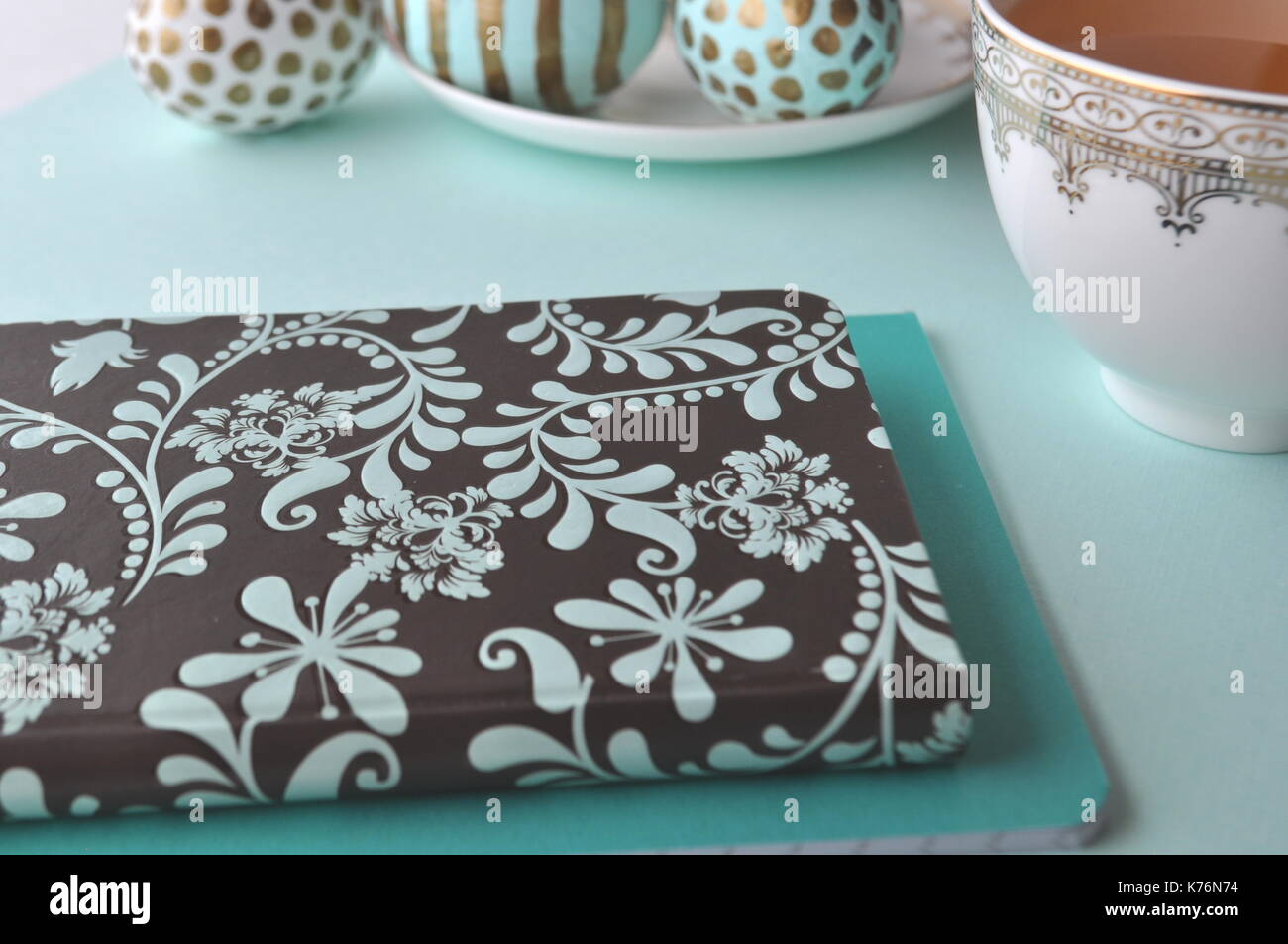 Oeufs de Pâques décorés avec bloc-notes florales et une tasse de thé à la menthe sur fond turquoise bleu sarcelle aqua with copy space Banque D'Images
