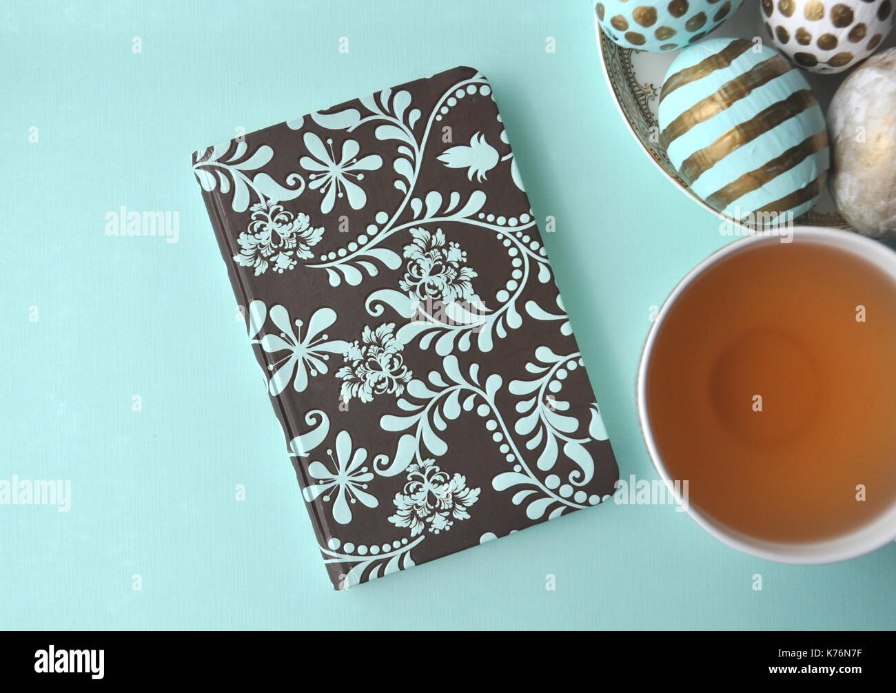 Oeufs de Pâques décorés avec bloc-notes florales et une tasse de thé à la menthe sur fond turquoise bleu sarcelle aqua with copy space Banque D'Images