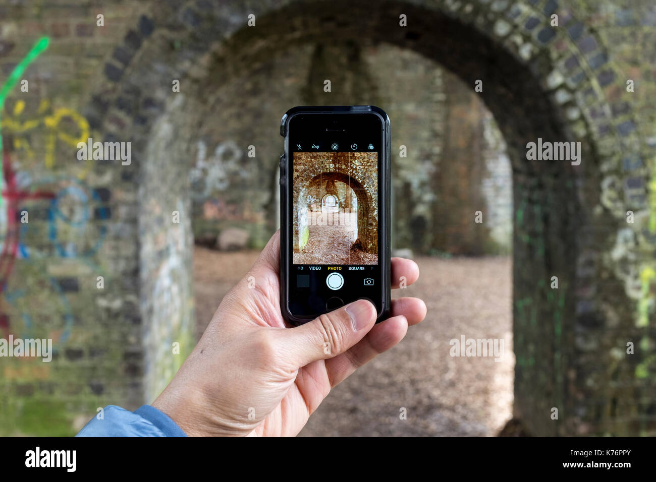 Un homme prenant des photos d'un viaduc de chemin de fer avec un iPhone SE smartphone, UK Banque D'Images