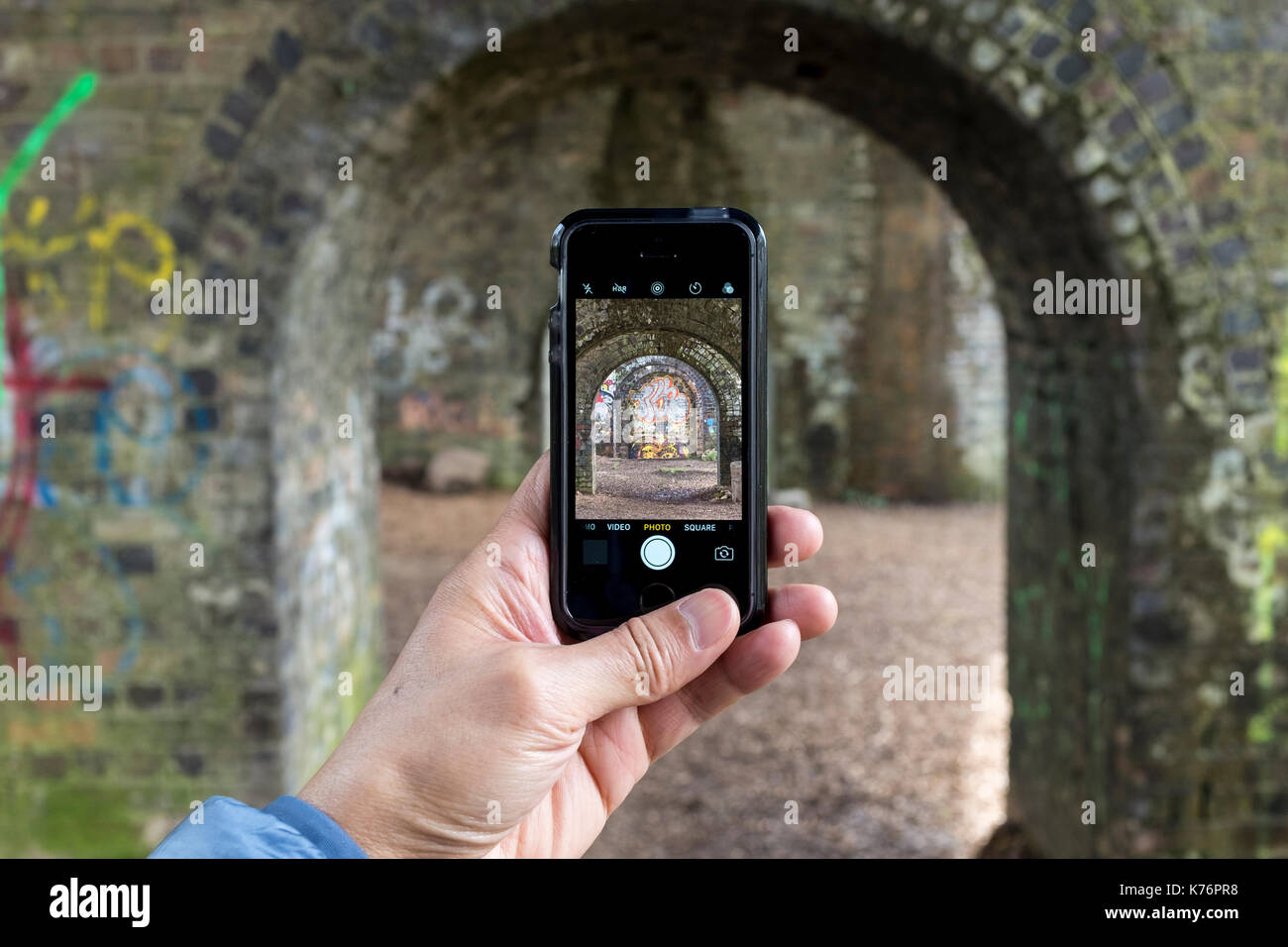 Un homme prenant des photos d'un viaduc de chemin de fer avec un iPhone SE smartphone, UK Banque D'Images