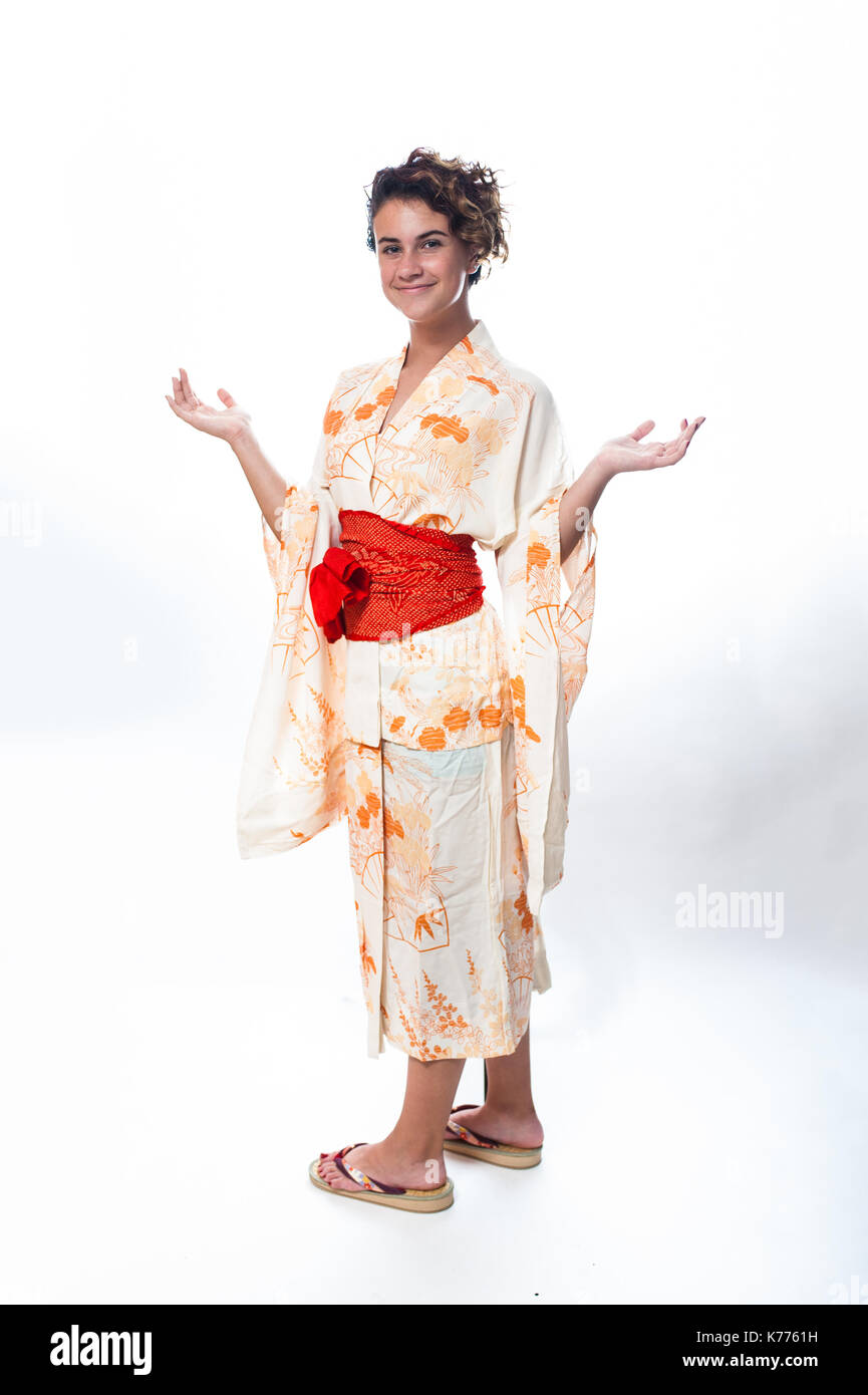 Fille de l'âge des adolescents habillés en kimono yukata japonais décontracté avec les bras pliés à coudes et les paumes vers le haut. Banque D'Images