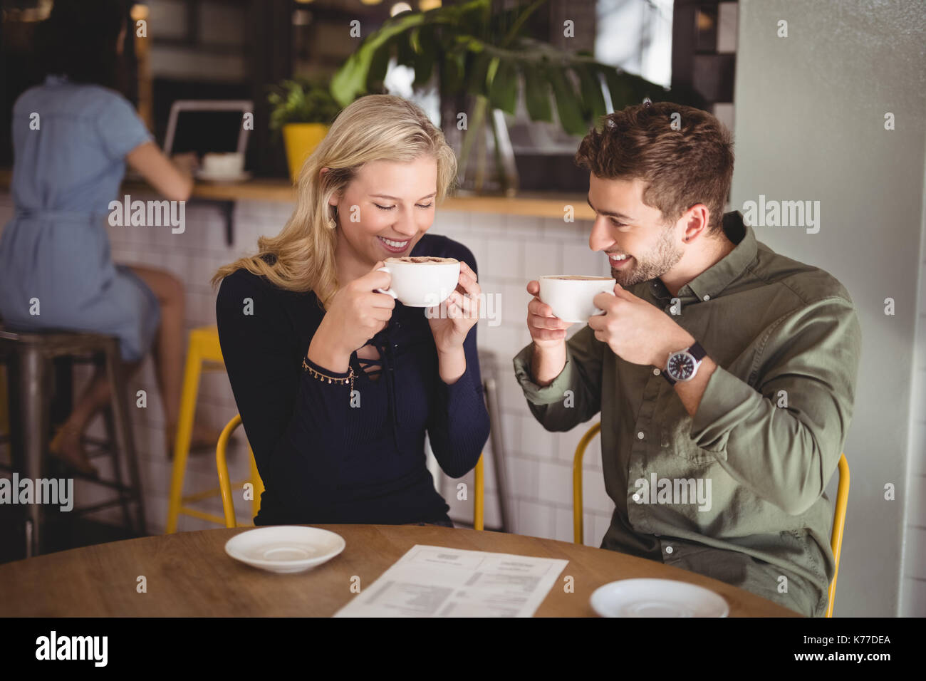 Smiling young couple drinking coffee while sitting at table in cafe Banque D'Images