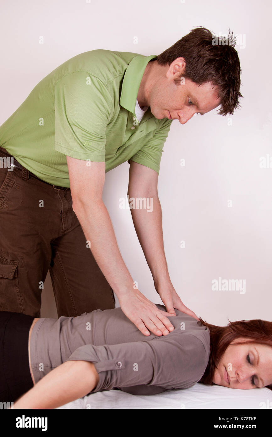 Un homme donnant un massage dos à une femme aux cheveux rouges. Banque D'Images