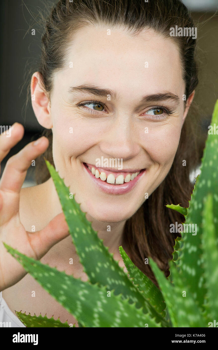 Jeune femme toucing l'usine de vera d'aloès et de rire Banque D'Images