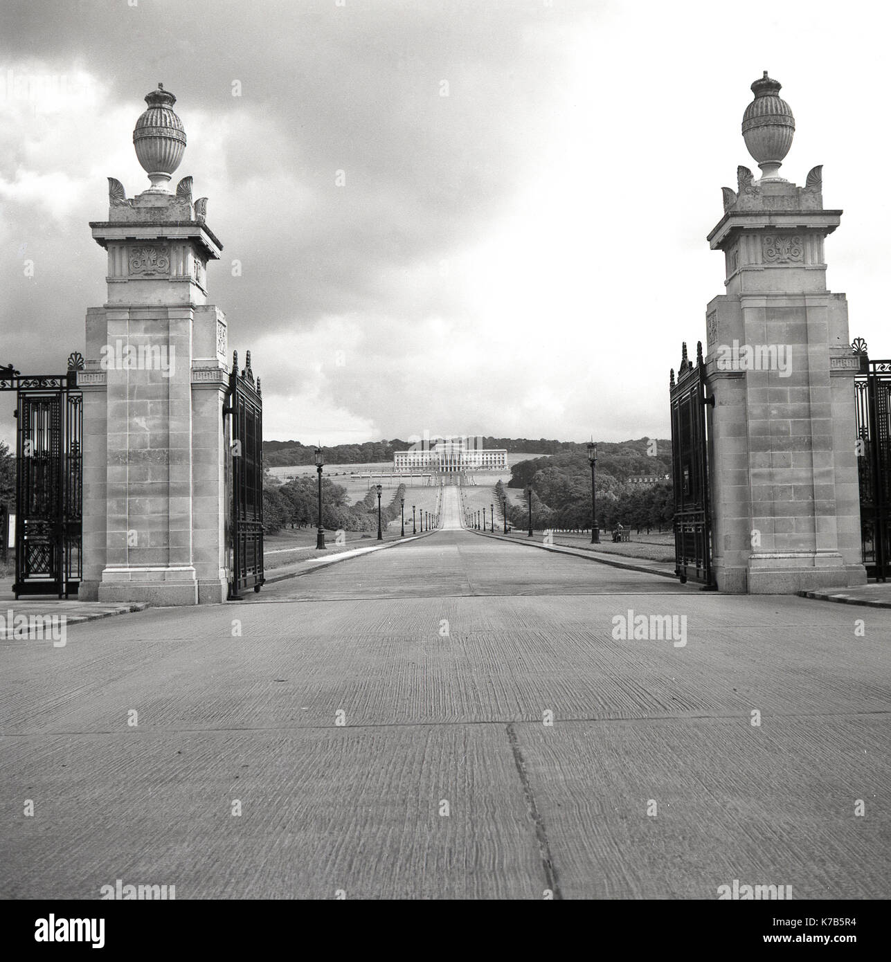 Années 1950, tableau historique des portes et l'entrée au parc et succession de Stormont, à Belfast, en Irlande du Nord, avec le grand bâtiment à la fin de la longue allée conçu dans un style classique grec, l'accueil de l'Assemblée d'Irlande du Nord (Parlement) depuis 1998. Banque D'Images