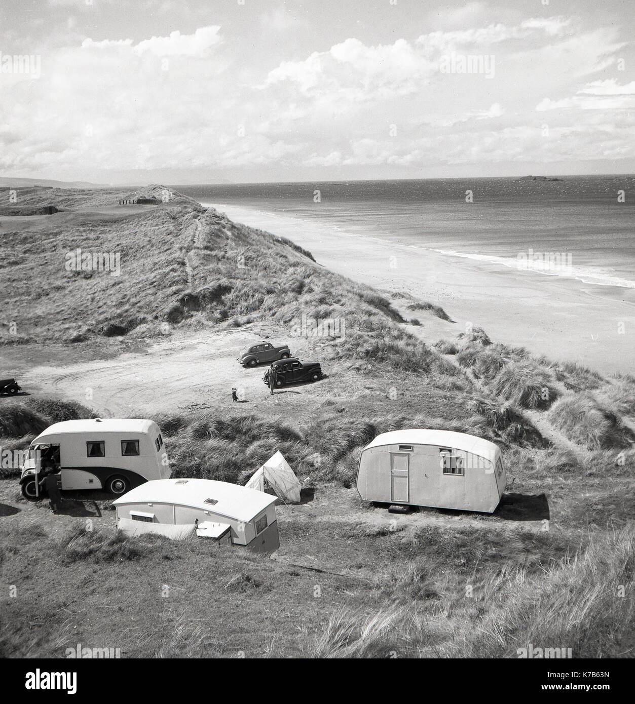 Années 1950, historique, un camping-car, deux caravanes et une petite tente sur les dunes de sable sur une belle portion de littoral par une longue plage de sable fin, l'Irlande du Nord, Royaume-Uni. Banque D'Images