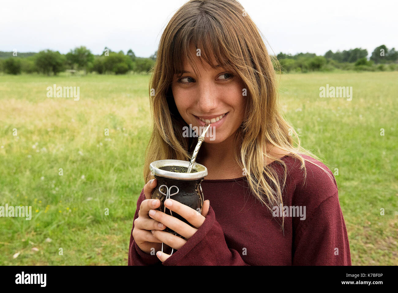 Jeune femme à boire la yerba mate de gourd outdoors Banque D'Images