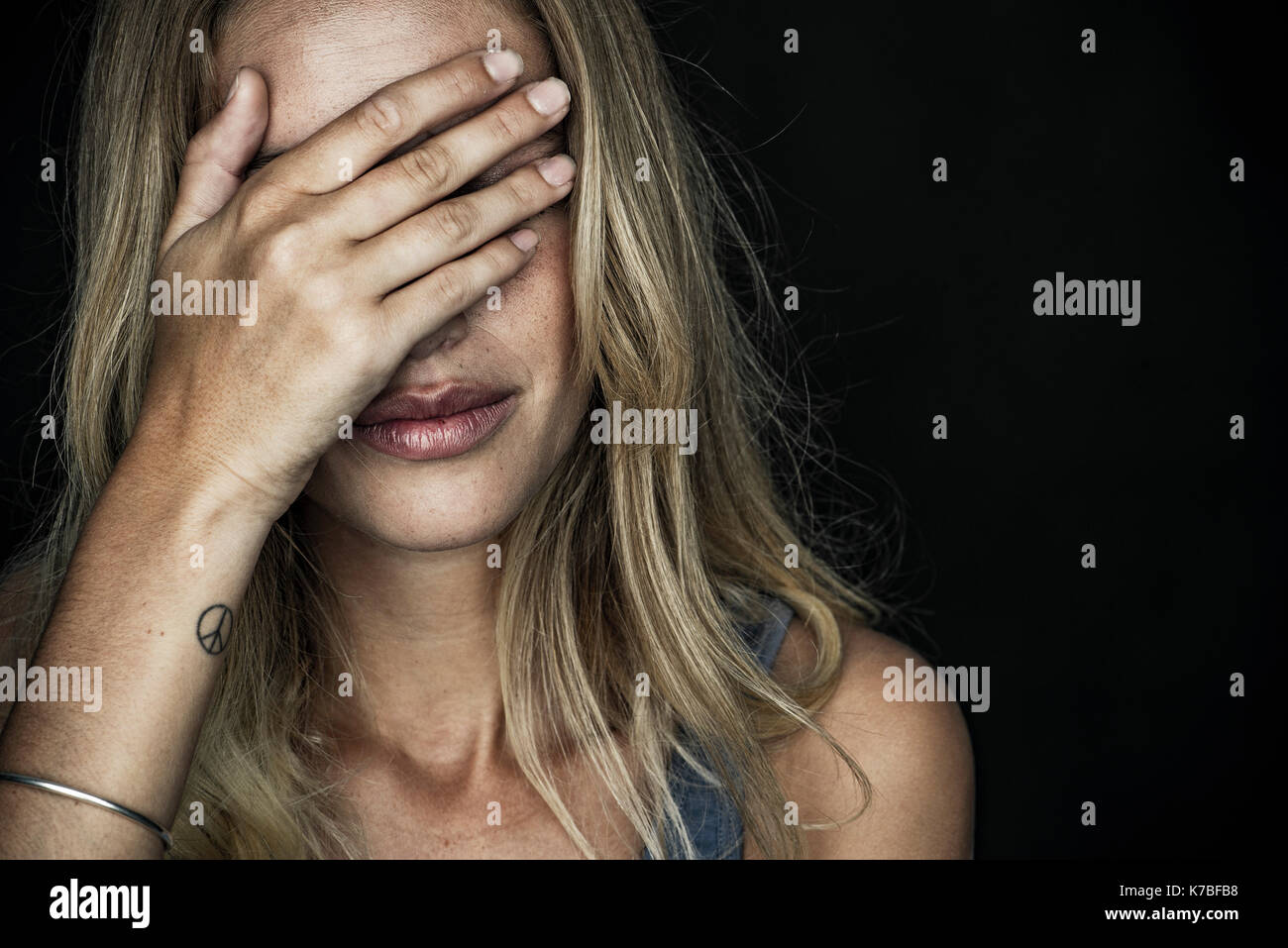 Woman covering face with hand Banque D'Images