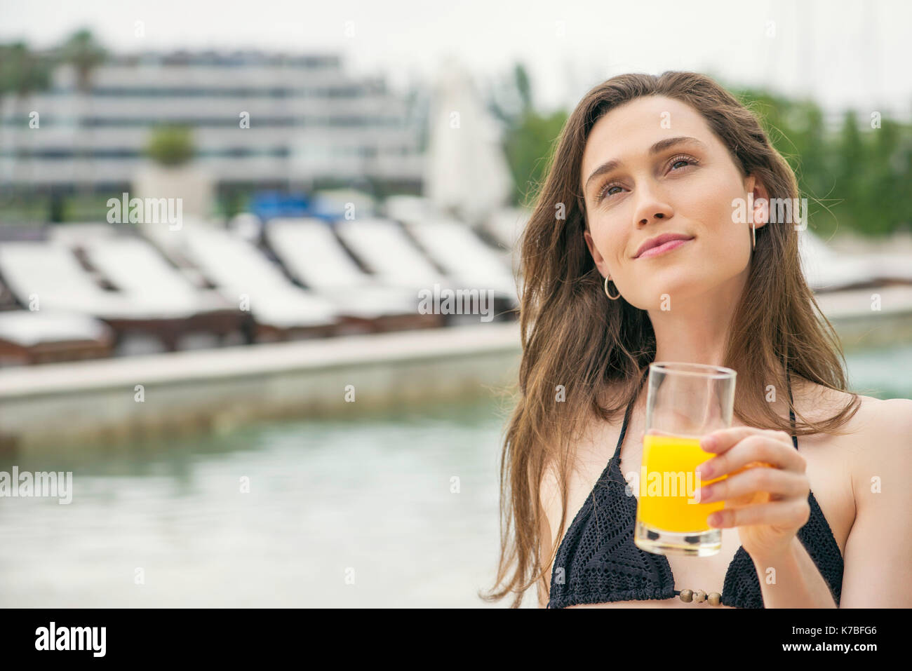 Femme boire du jus à côté piscine Banque D'Images