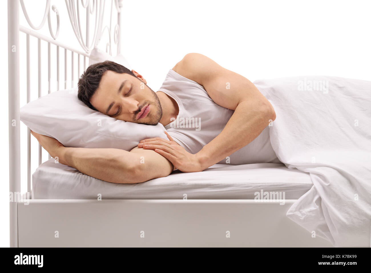 Jeune homme dormir dans un lit isolé sur fond blanc Banque D'Images