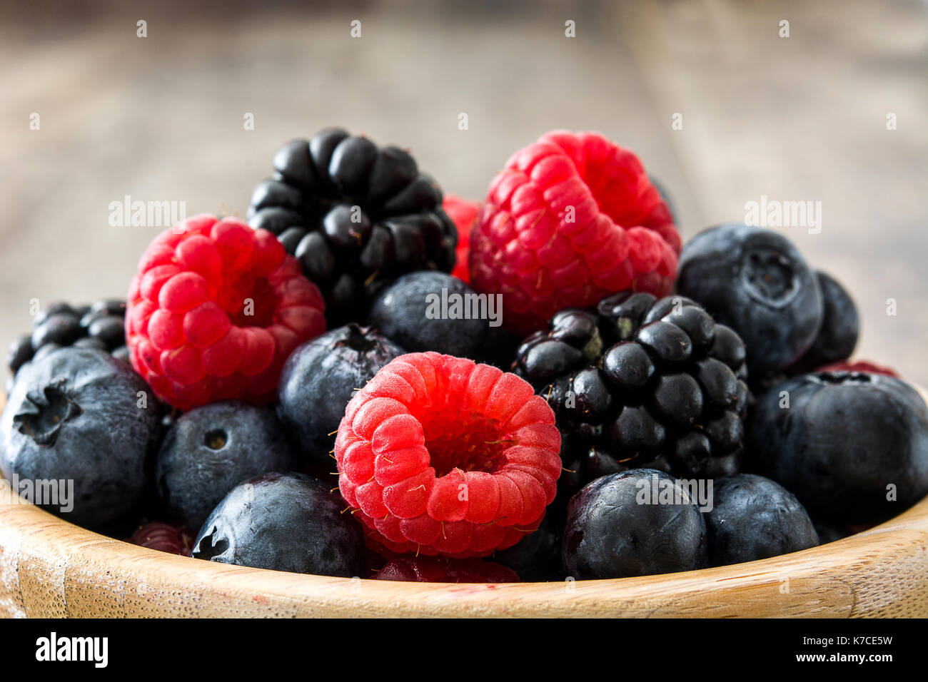 Petits fruits sains à bol en bois sur table en bois Banque D'Images