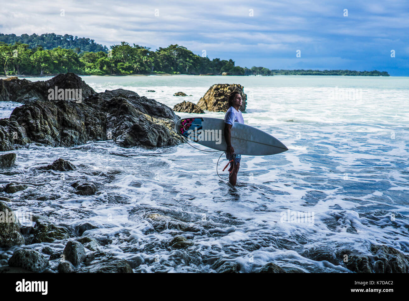 Vue latérale du surfer carrying surfboard debout at beach Banque D'Images