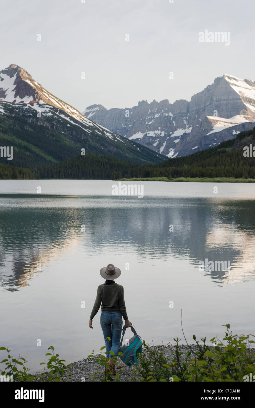 Vue arrière du female hiker looking at Mt. Grinnell en position debout par Swiftcurrent Lake Banque D'Images