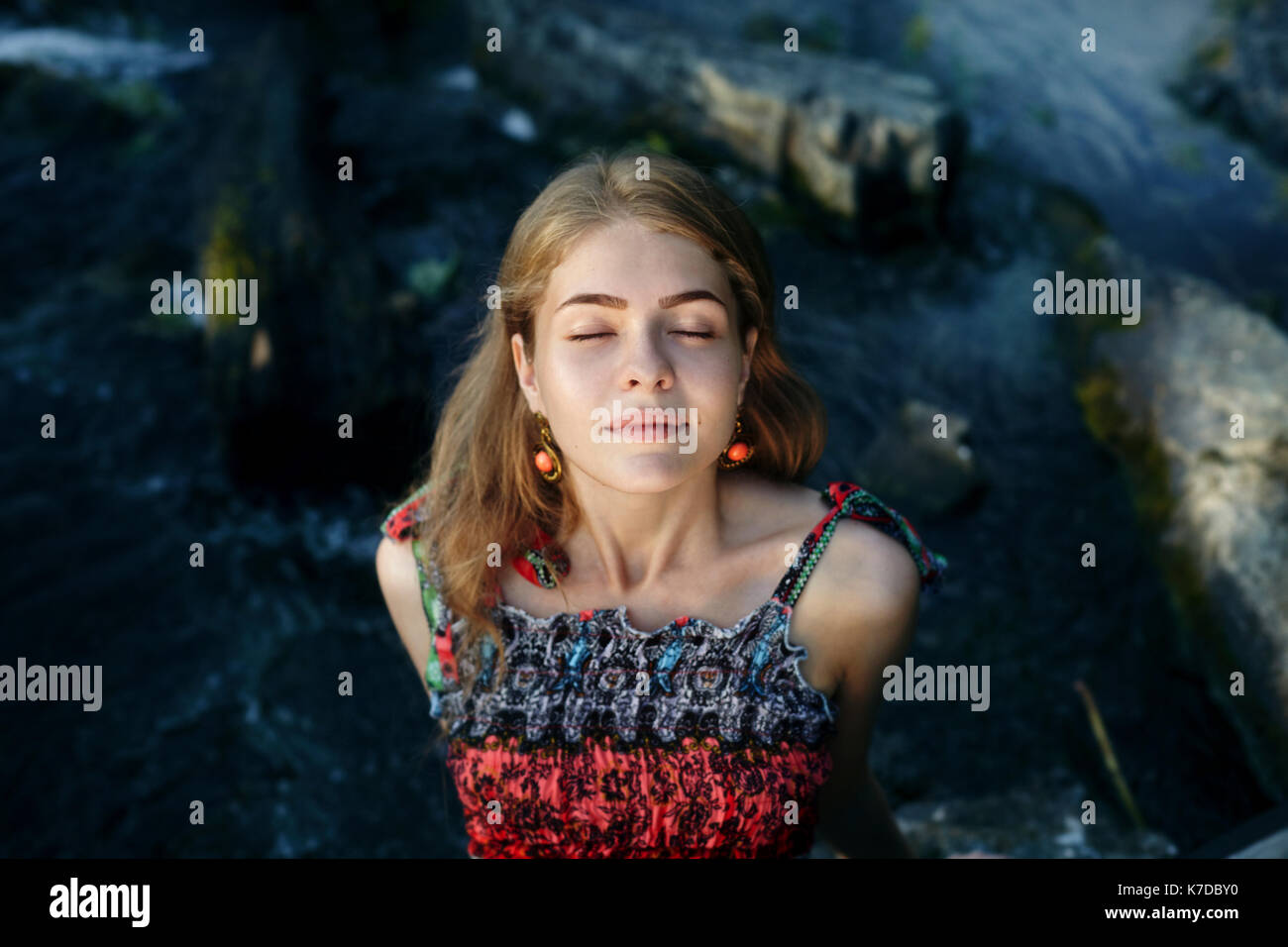 High angle view of woman with eyes closed assis sur des rochers Banque D'Images