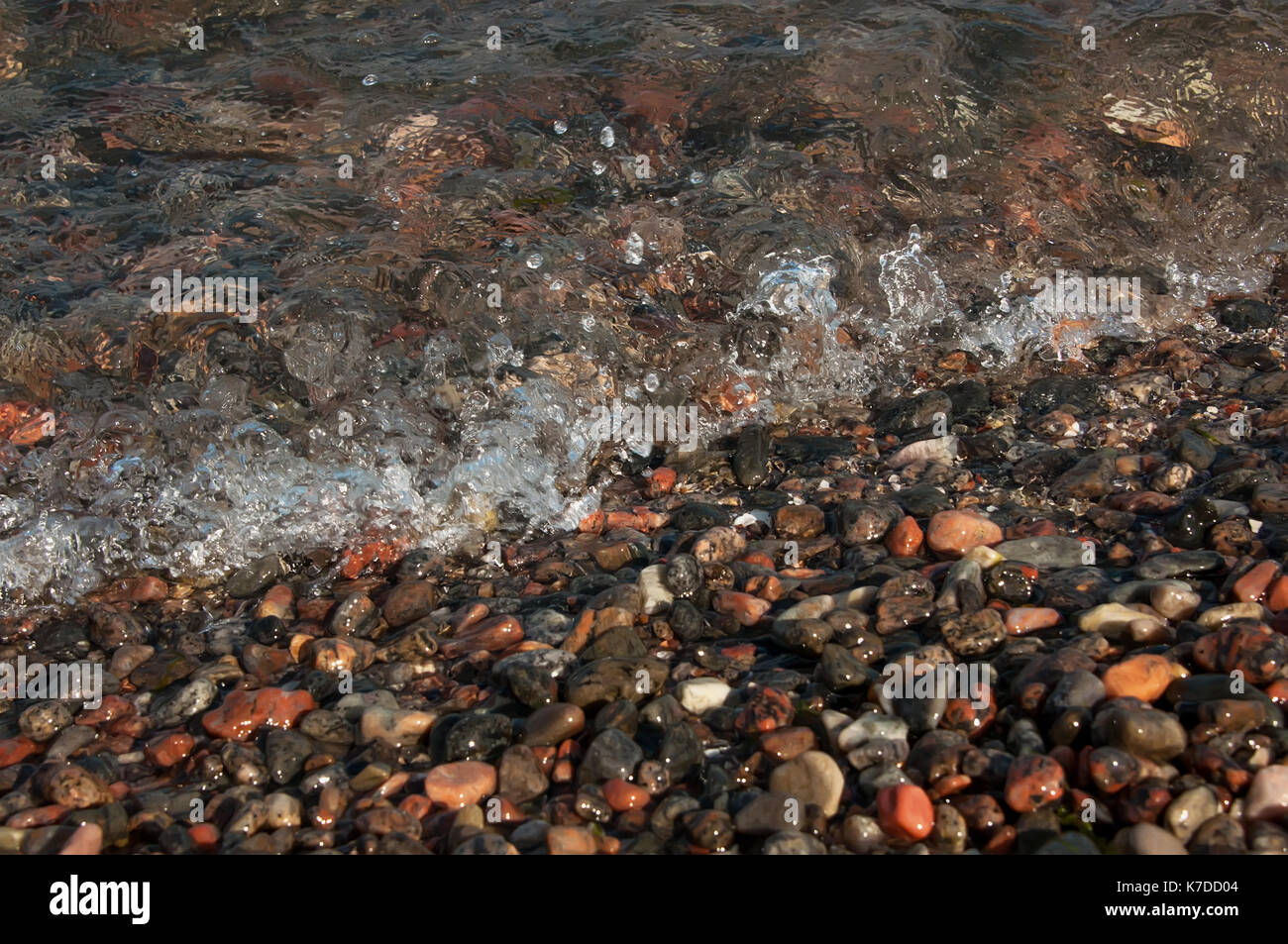 La plage de pierres multicolores sur la frontière de la surf résumé fond selective focus Banque D'Images