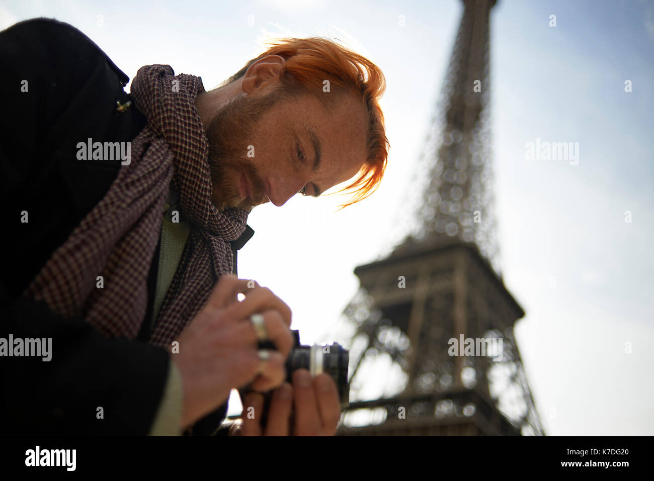 Low angle view of man watching photos sur votre appareil photo reflex numérique contre la Tour Eiffel Banque D'Images