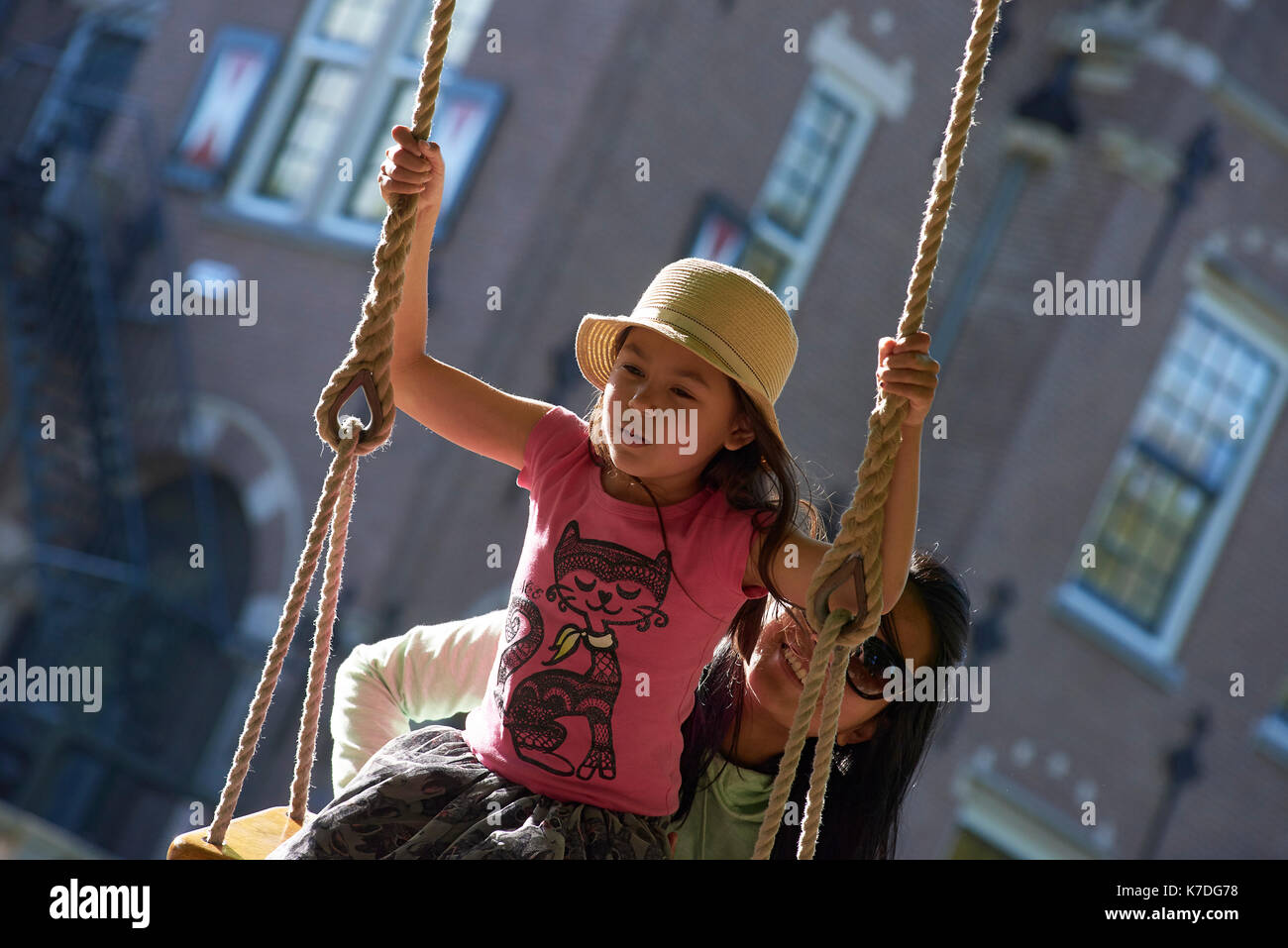 Heureux mère poussant swing corde pour fille à l'aire de jeux Banque D'Images