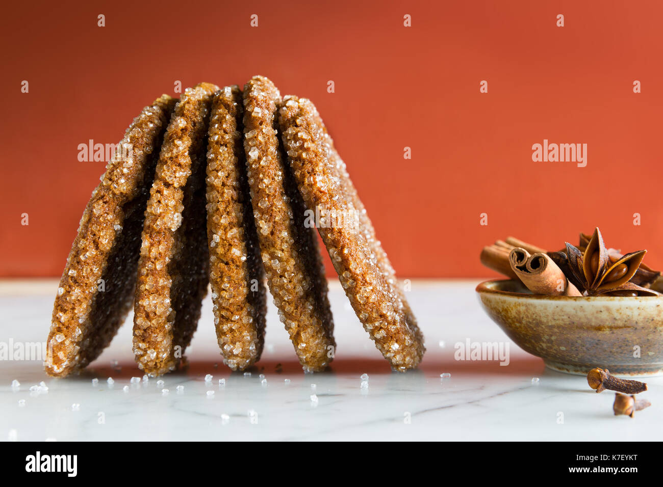 Le gingembre spice cookies avec des cristaux de sucre. Le marbre blanc comptoir. fond orange foncé. Banque D'Images