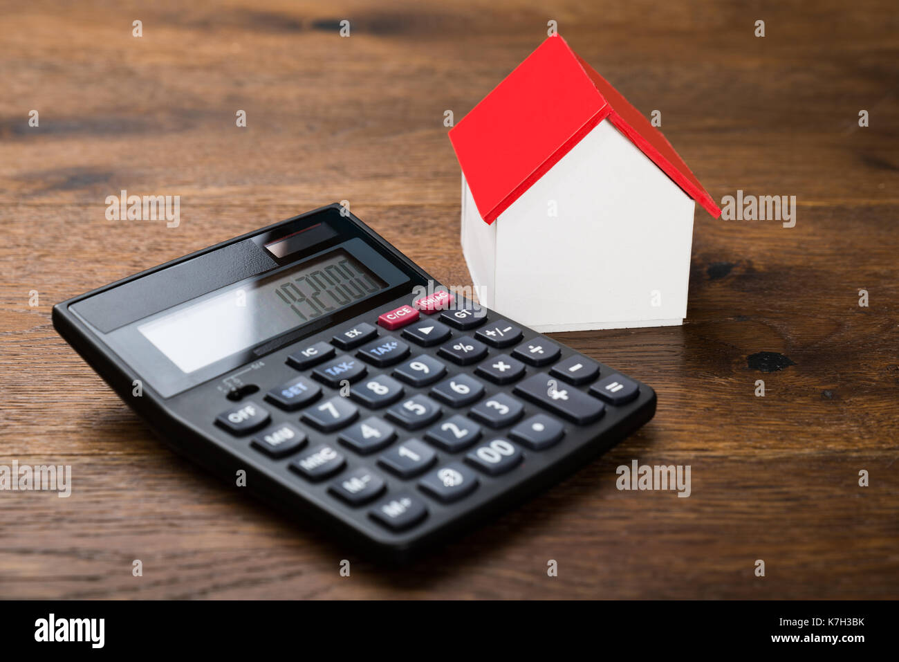 Close-up of miniature house avec la calculatrice sur table en bois Banque D'Images
