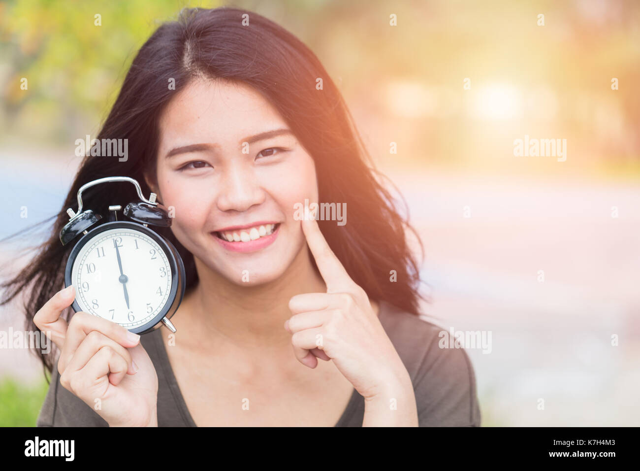Les femmes asiatiques et thaïlandais montrent point son visage de côté avec l'horloge, le temps faire marche arrière pour la peau de bébé concept. Banque D'Images