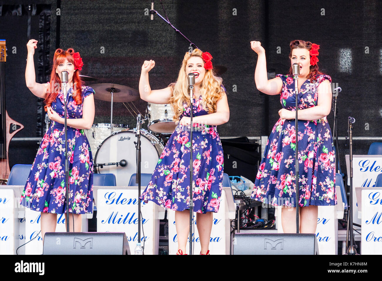 La Polka Dot Poupées, trio populaires qui chantent des chansons nostalgiques des années de guerre 1939-45, chanter sur scène à l'hommage aux années 40 week-end à Cran-gevrier. Vue avant d'entre eux debout chantant en face de microphones. Banque D'Images