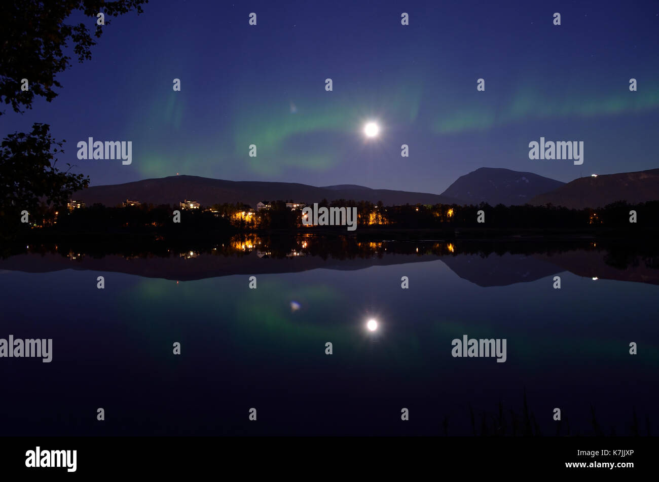 Aurora Borealis, majestueux northern light sur le lac Miroir calme la nuit avec des bâtiments en arrière-plan Banque D'Images