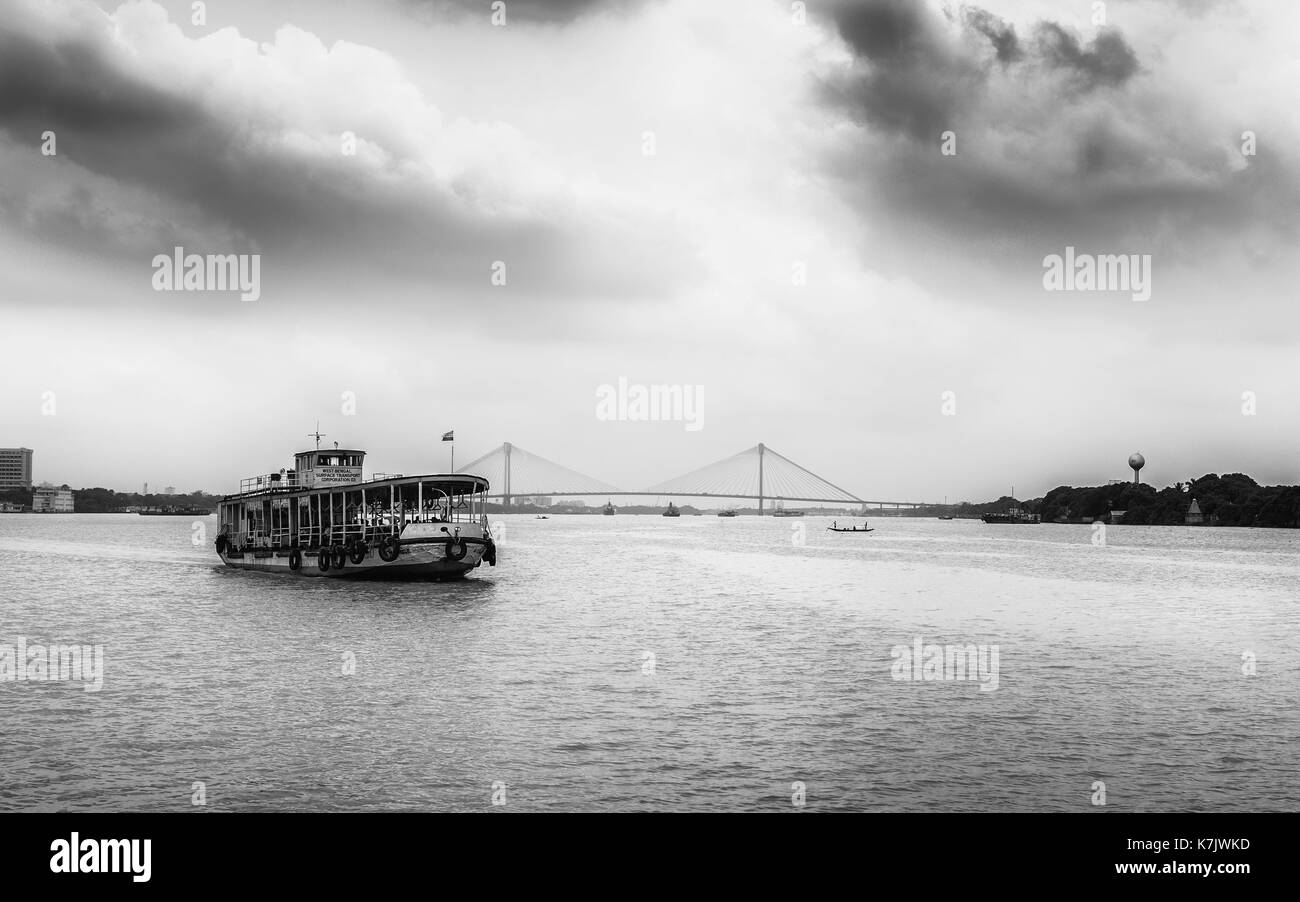 Le ferry public traverse la rivière Hooghly sur la mousson couvert le matin avec vue sur le nouveau pont Howrah en arrière-plan à Kolkata, Inde. Banque D'Images