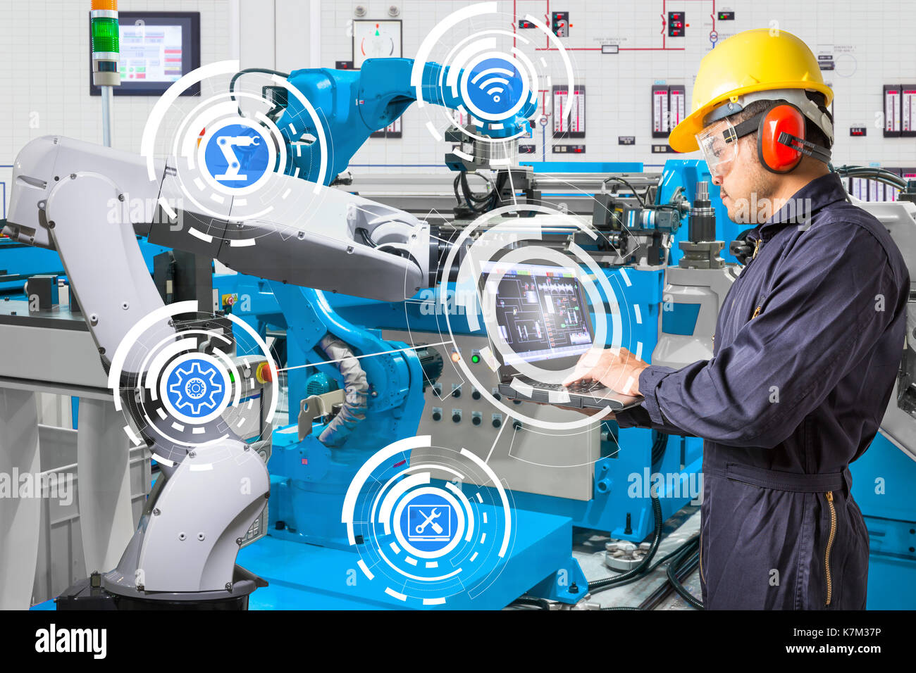 Ordinateur portable à l'aide de l'ingénieur pour l'entretien de la machine-outil main robotisée automatique à l'usine de fabrication industrielle Banque D'Images