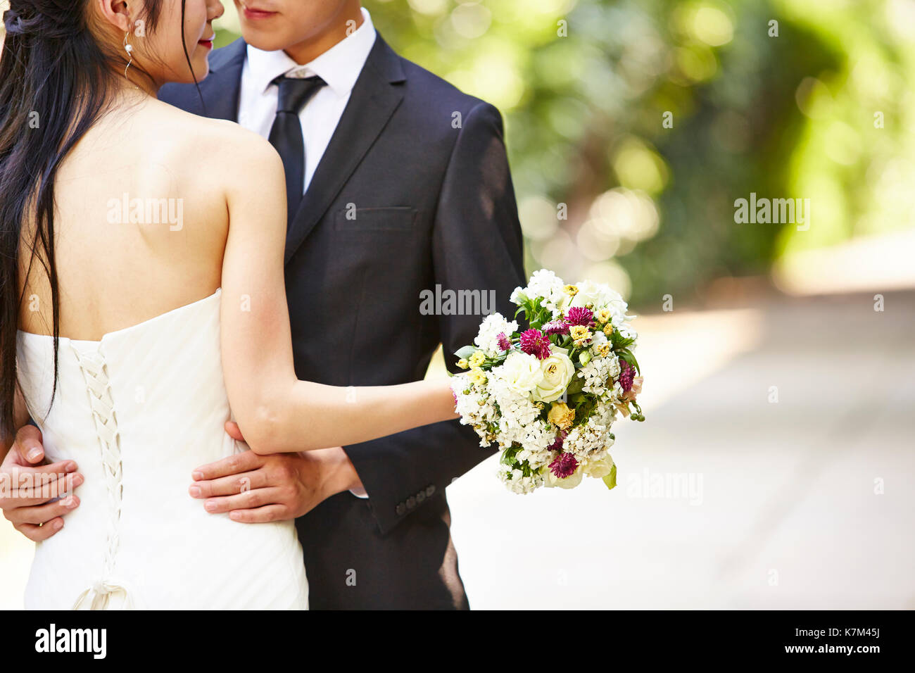 Asian wedding couple hugging les uns les autres, se concentrer sur le bouquet. Banque D'Images