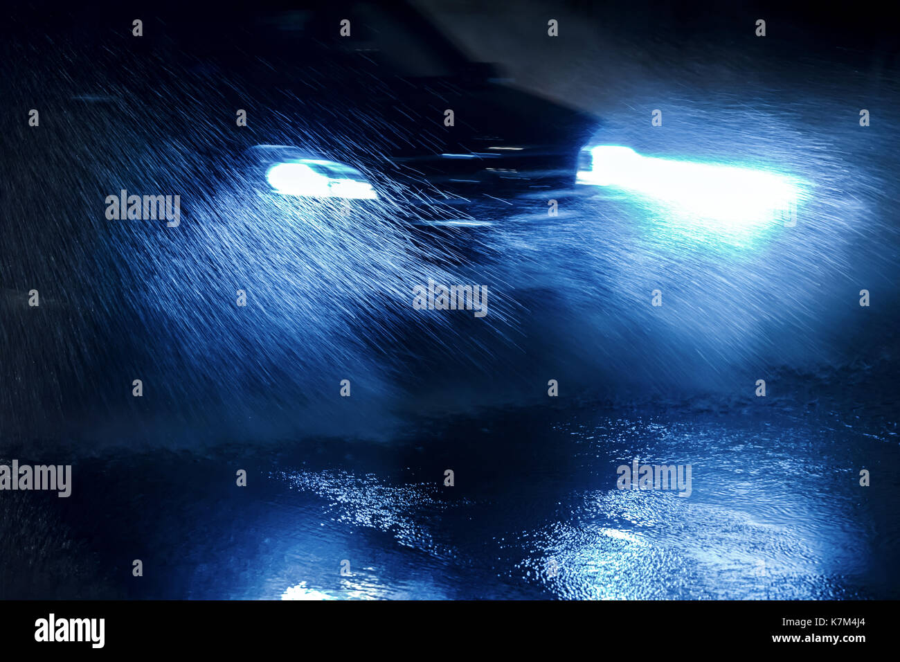 Voiture roulant à travers la forte pluie avec commutation sur phares bleu Banque D'Images