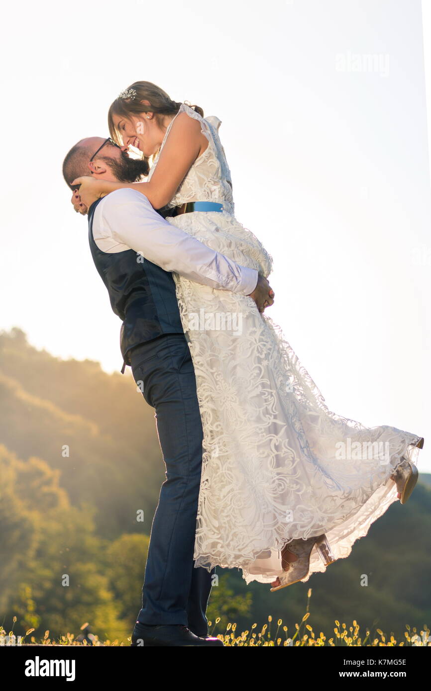 Groom holding mariée dans ses bras, mariage couple having fun Banque D'Images